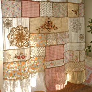 May include: A patchwork curtain made from various fabrics, including floral prints, gingham, and lace. The curtain features embroidered details and crochet doilies, giving it a vintage, handmade look. It is suspended from a wooden rod.