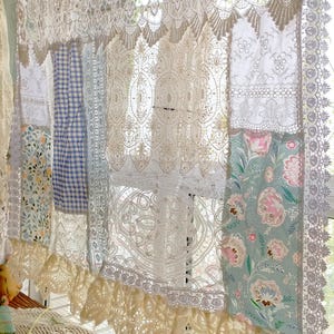 Peut inclure: Un rideau en dentelle blanche avec un motif patchwork composé de motifs floraux et à carreaux. Le rideau a un ourlet inférieur à volants et est fait de dentelle délicate.