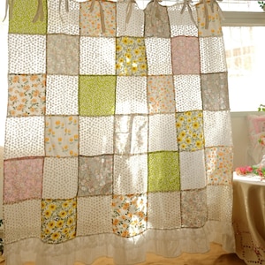 Può includere: Una tenda patchwork con una varietà di motivi floreali e a pois nei toni del verde, giallo, rosa e grigio. La tenda è appesa con lacci di tessuto e ha un bordo a balze nella parte inferiore.