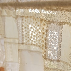 Puede incluir: Una cortina de encaje blanco con un dise&ntilde;o de patchwork. El encaje est&aacute; hecho de diferentes patrones y texturas, creando un aspecto &uacute;nico y elegante.
