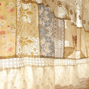 Peut inclure: Un rideau en crochet blanc avec un bord festonné et un motif patchwork composé de motifs floraux et géométriques. Le rideau est fait de dentelle délicate et est parfait pour ajouter une touche de charme vintage à n'importe quelle pièce.