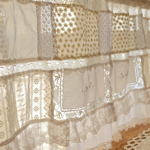 Puede incluir: Una cenefa de encaje blanco con un dise&ntilde;o de patchwork. La cenefa est&aacute; hecha de diferentes tipos de encaje, incluyendo encaje de ojal, encaje de ganchillo y encaje bordado. La cenefa est&aacute; adornada con un volante.