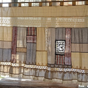 Può includere: Una tenda patchwork nei toni del beige, grigio e rosa. Presenta una varietà di tessuti con diversi motivi, tra cui quadri, righe e pizzo floreale. Il bordo inferiore ha un bordo in pizzo smerlato.