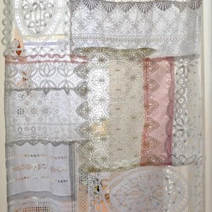 Peut inclure: Panneaux de rideaux en dentelle blanche avec divers motifs floraux et géométriques. Les panneaux sont superposés, créant un traitement de fenêtre texturé. Le design comprend des bords festonnés et des motifs floraux.