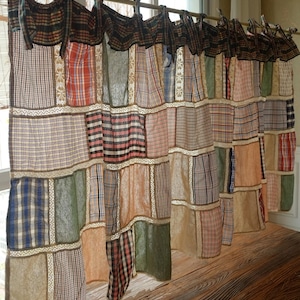 Può includere: Tenda patchwork con una varietà di tessuti a quadri e tinta unita. La tenda presenta un mix di colori tra cui marrone, rosso, blu, verde e beige. La tenda è appesa a un'asta con lacci di tessuto.