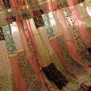 Könnte beinhalten: Ein Patchwork-Vorhang mit verschiedenen Stoffen mit Blumen-, Vichy- und anderen Mustern in Rosa, Braun und Türkis. Der Vorhang hat eine Rüschenspitze am unteren Rand, was ihm einen Vintage- und Bohème-Look verleiht.