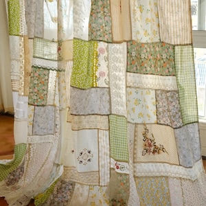 Peut inclure: Rideaux patchwork composés de divers tissus, dont des motifs floraux, de la dentelle et des rayures. Les couleurs dominantes sont le vert, le blanc et le beige. Les rideaux sont suspendus à une tringle en bois avec des attaches en tissu.