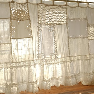 May include: Cream-colored patchwork curtain with various lace and embroidered panels. The curtain features a mix of textures, including delicate lace edging and floral embroidery, creating a vintage, romantic aesthetic. The curtain is hung on a wooden rod.