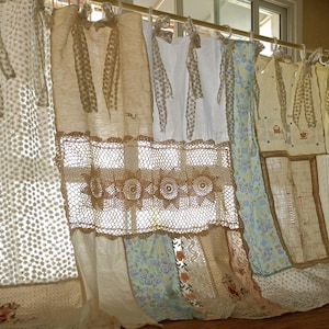 May include: A display of vintage-style curtains in diverse designs and fabrics. The curtains feature lace, floral patterns, and crochet details. They hang from a gold-coloured rod, creating a layered and textured display. The colour palette is soft, with beige, white, and pastel hues.