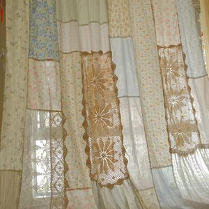 Può includere: Tende patchwork con una varietà di tessuti floreali e fantasia in colori pastello. Le tende presentano pannelli decorativi all'uncinetto con un motivo floreale, aggiungendo un'estetica vintage e artigianale al trattamento della finestra.