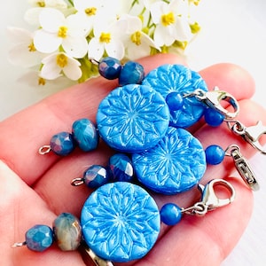 May include: Three blue snowflake-shaped charms with silver lobster clasps and blue glass beads.