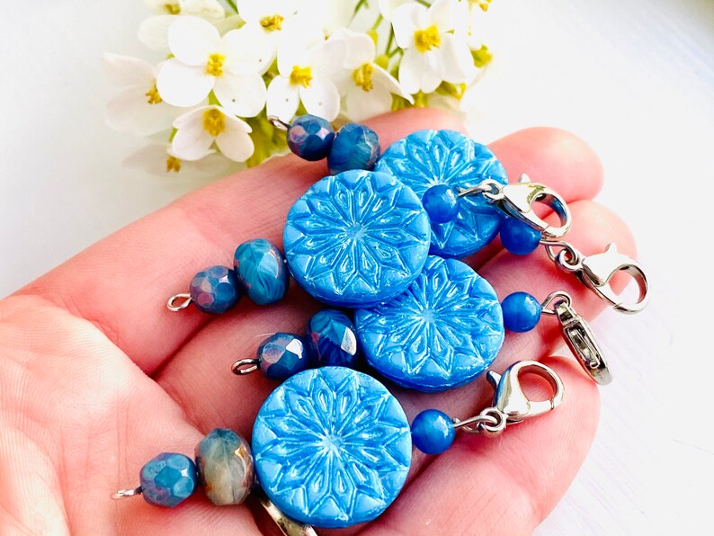 May include: Three blue snowflake-shaped charms with silver lobster clasps and blue glass beads.
