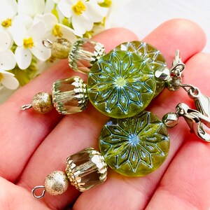 May include: Green glass earrings with a snowflake design and silver beads and clasps.