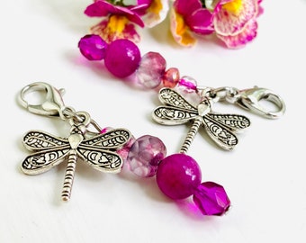 May include: A pink and silver dragonfly charm with a silver clasp. The charm is made with pink and purple beads and a silver dragonfly pendant.