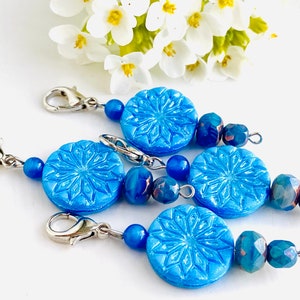 May include: Four blue snowflake-shaped bead charms with silver clasps and blue and iridescent glass beads.