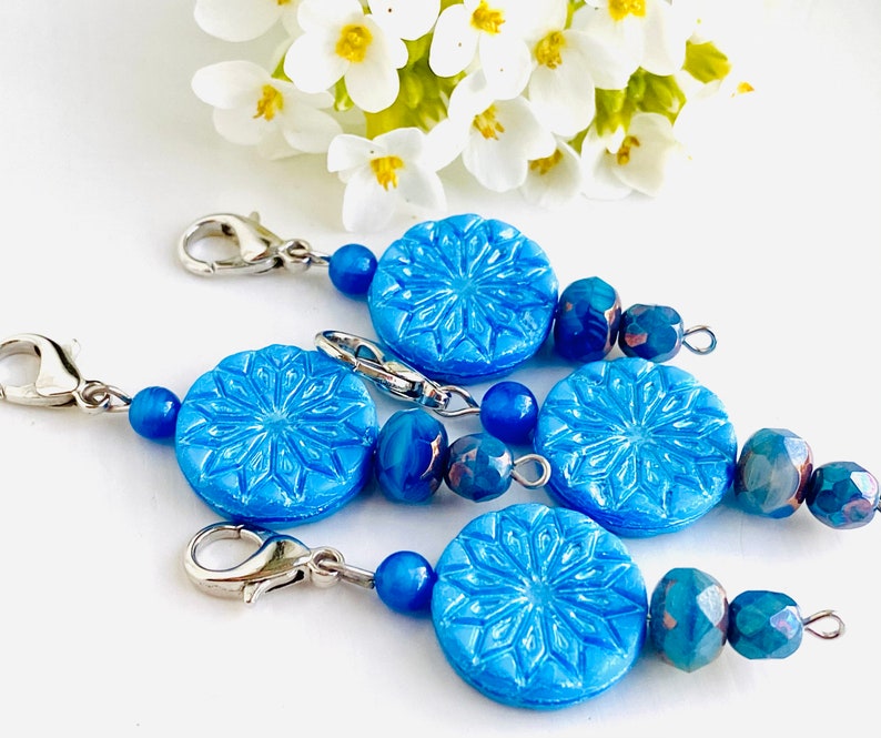 May include: Four blue snowflake-shaped bead charms with silver clasps and blue and iridescent glass beads.
