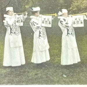 May include: Vintage postcard featuring four individuals in white costumes with hats, holding trumpets and banners. The text reads "Old English Pageant" and "Heralds." The image is from State Normal College, Greensboro, N.C., dated May 20th, 1916.