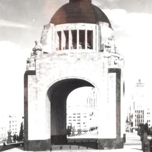 May include: Black and white photograph of a large stone monument with a domed roof and an arched entrance. The monument has classical architectural details and is set against a cloudy sky. Buildings are visible in the background.