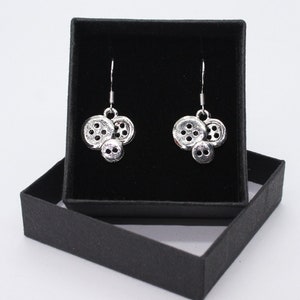 May include: A pair of silver earrings shaped like three buttons, presented in a black velvet jewellery box.