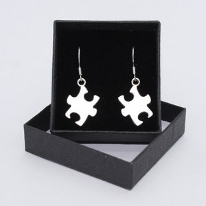 May include: A pair of silver puzzle piece earrings in a black gift box.
