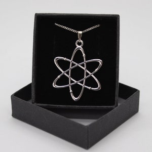 May include: A silver atom pendant necklace in a black velvet box. The necklace features a detailed atom design with a chain.