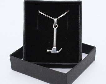 May include: A silver hammer pendant necklace in a black velvet box. The necklace is on a silver chain.