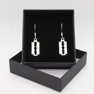 May include: A pair of silver razor blade earrings in a black velvet jewelry box.