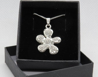 May include: A silver necklace with a flower pendant. The pendant is made of silver and has a swirling pattern of circles.
