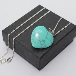 May include: A turquoise heart-shaped pendant necklace with a silver chain. The necklace is displayed in a black gift box.