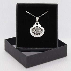 May include: A silver pendant necklace with a religious icon in a black velvet box.