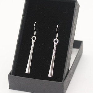 May include: A pair of silver baseball bat earrings in a black velvet jewellery box.