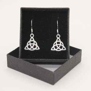 May include: A pair of silver Celtic knot earrings in a black velvet box. The earrings are in the shape of a triangle with a knot design.