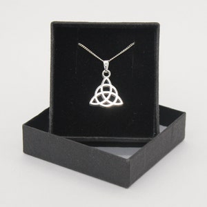 May include: A silver Celtic knot pendant necklace in a black velvet box. The pendant is a triangular shape with a knot design.