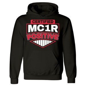 以下が含まれることがあります： 「CERTIFIED MC1R POSITIVE」と書いてある赤と白のグラフィックが施された黒いフード付きスウェットシャツです。