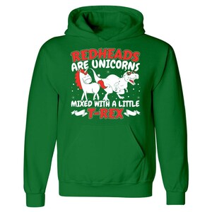 K&ouml;nnte beinhalten: Gr&uuml;ner Kapuzenpullover mit einem wei&szlig;en Einhorn und einem roten T-Rex-Motiv. Der Text lautet "Rothaarige sind Einh&ouml;rner, die mit einem kleinen T-Rex vermischt sind."
