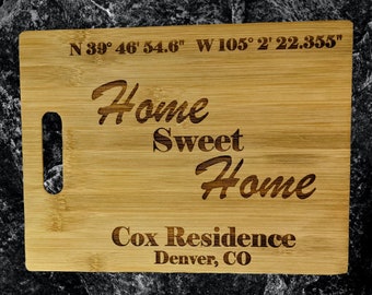 May include: A light brown wooden cutting board with the text "Home Sweet Home" and "Cox Residence Denver, CO" engraved on it. The coordinates "N 39° 46' 54.6" W 105° 2' 22.355" are also engraved on the board.