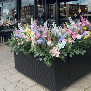 以下が含まれることがあります： 黒い看板に「LOCCO BRUNCH | DESSERT | DRY-BAR」と書かれた店先。店先には黒いプランターにカラフルな花が飾られている。看板は黒い背景に金色の文字で書かれている。