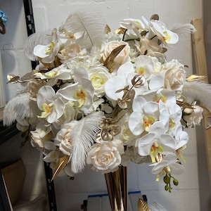 K&ouml;nnte beinhalten: Ein wei&szlig;-goldener Blumenstrau&szlig; mit Orchideen, Rosen und Federn in einer goldenen Vase. Der Strau&szlig; ist perfekt f&uuml;r eine Hochzeit, eine Party oder einen besonderen Anlass.