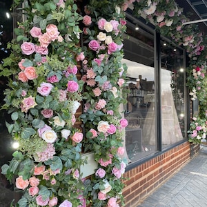 VETRINA DEL NEGOZIO Ghirlanda di fiori rosa e verdi - Esposizione della vetrina frontale con fiori rosa e fogliame