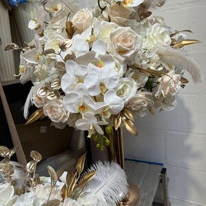 K&ouml;nnte beinhalten: Ein gro&szlig;er wei&szlig;er und cremefarbener Blumenstrau&szlig; mit goldenen Akzenten. Der Strau&szlig; besteht aus Orchideen, Rosen und Hortensien. Er ist perfekt f&uuml;r eine Hochzeit oder einen besonderen Anlass.