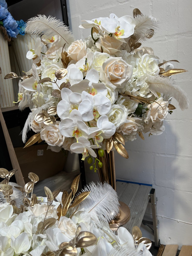 K&ouml;nnte beinhalten: Ein gro&szlig;er wei&szlig;er und cremefarbener Blumenstrau&szlig; mit goldenen Akzenten. Der Strau&szlig; besteht aus Orchideen, Rosen und Hortensien. Er ist perfekt f&uuml;r eine Hochzeit oder einen besonderen Anlass.