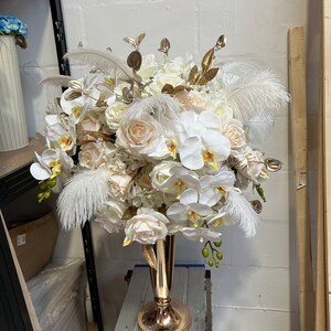 K&ouml;nnte beinhalten: Ein gro&szlig;er wei&szlig;er und cremefarbener Blumenstrau&szlig; mit goldenen Akzenten in einer goldenen Vase. Der Strau&szlig; enth&auml;lt Orchideen, Rosen und Hortensien.