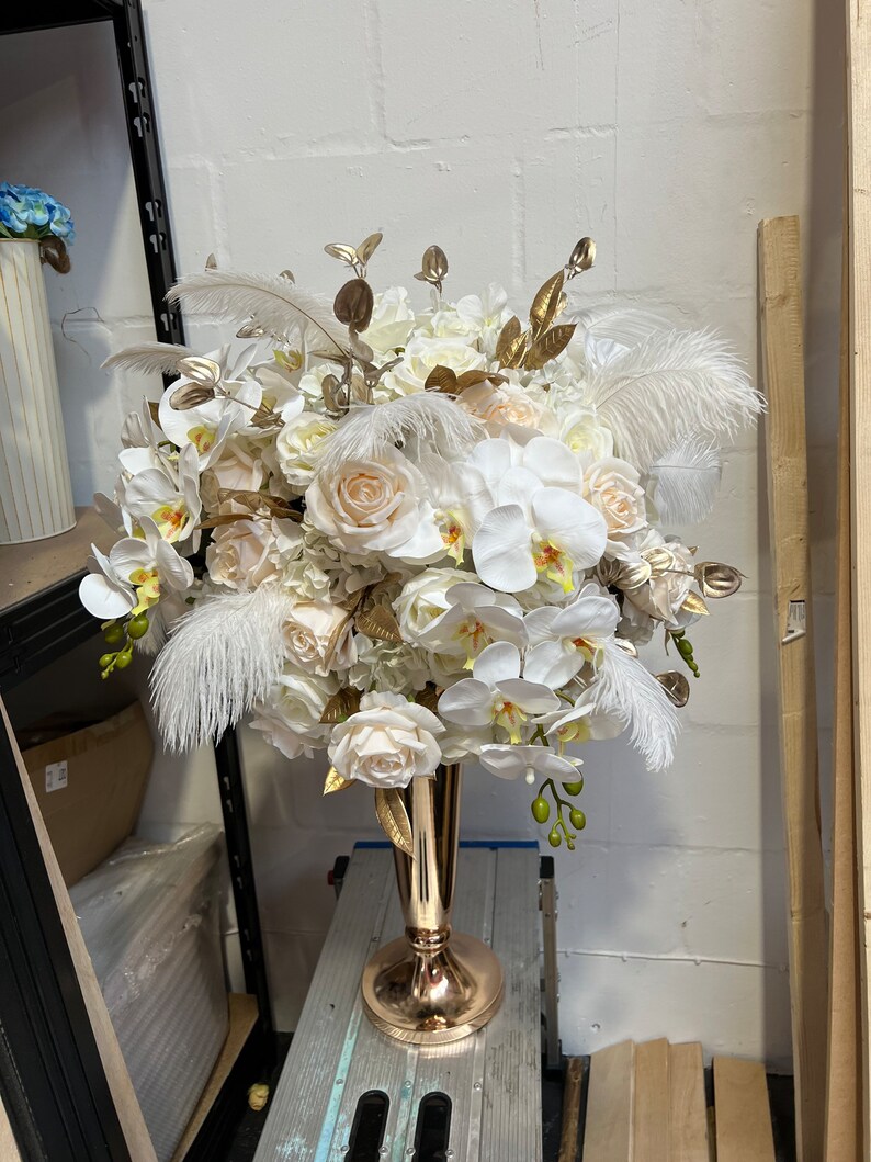 K&ouml;nnte beinhalten: Ein gro&szlig;er wei&szlig;er und cremefarbener Blumenstrau&szlig; mit goldenen Akzenten in einer goldenen Vase. Der Strau&szlig; enth&auml;lt Orchideen, Rosen und Hortensien.