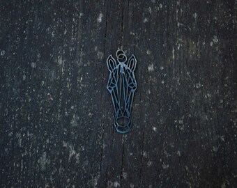 May include: A geometric zebra head cutout made of metal, with a black finish. The cutout is hanging on a dark wood background.
