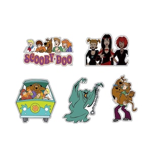 May include: A collection of colorful cartoon stickers featuring characters and elements from the animated series Scooby-Doo. The stickers include the Mystery Machine van, the Scooby-Doo logo, and various characters and villains.