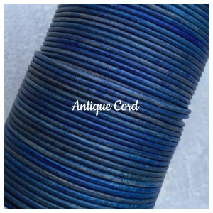 May include: Close-up of a spool of blue leather cord. The cord is tightly wound and has a slightly distressed look. The text "Antique Cord" is printed on the spool.