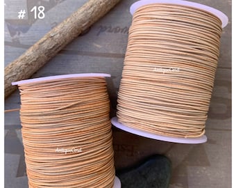 May include: Two spools of light brown leather cord, one larger than the other. The spools are labeled "AntiqueCord" and the smaller spool is labeled "#18".
