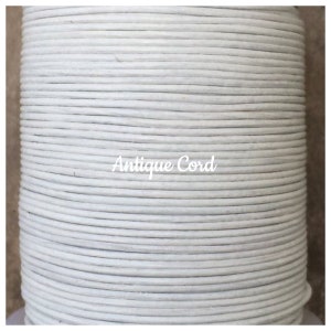 May include: A spool of white leather cord, labeled "Antique Cord".