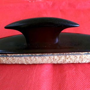 May include: A black shoe polisher with a cushioned surface and a handle shaped like a boat prow.
