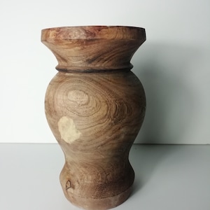 Peut inclure: Un vase en bois brun avec une base large et un col étroit. Le vase présente un motif de grain de bois naturel et une finition lisse.